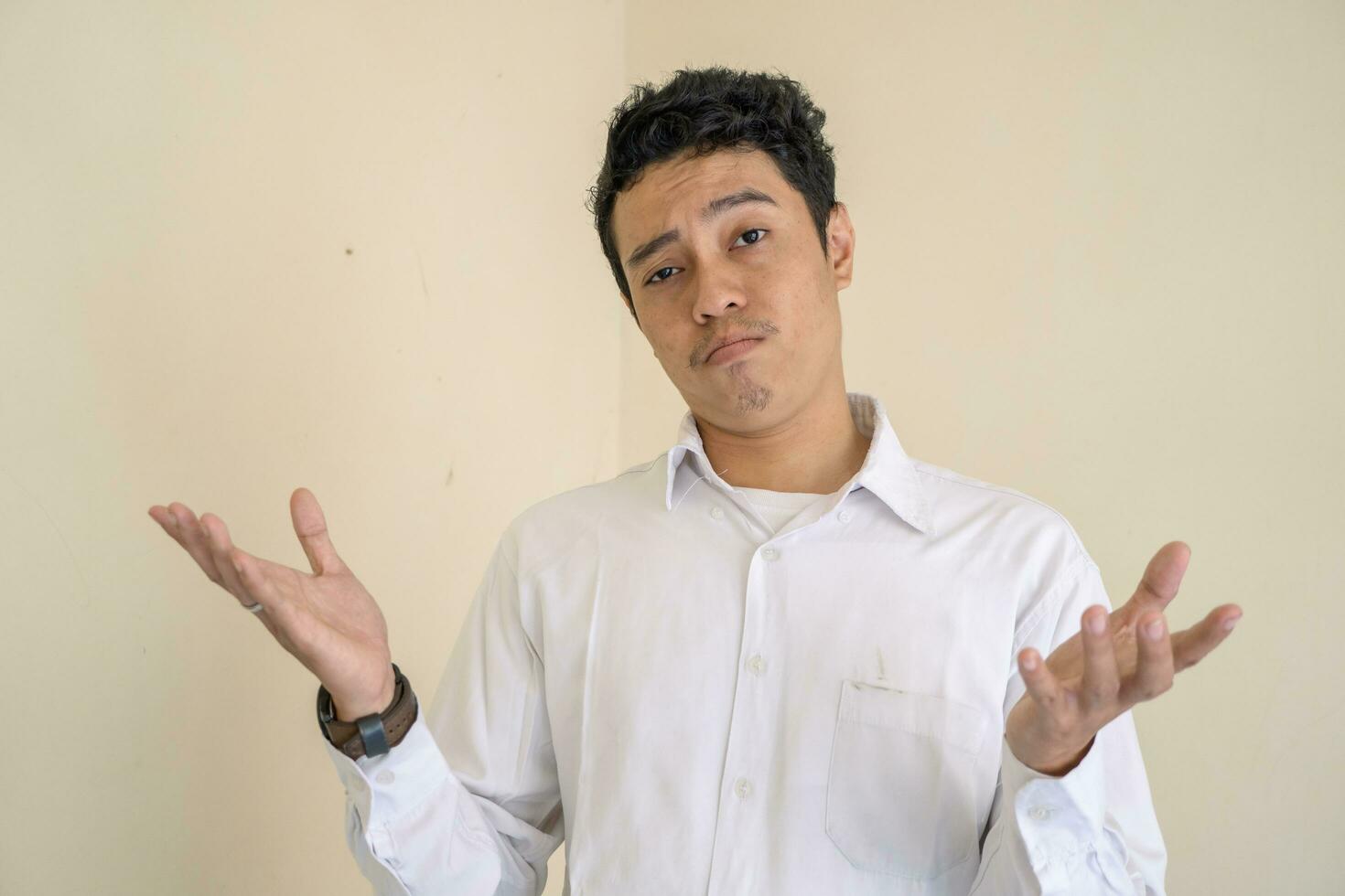 Young Indonesian curly man wear white clothes with i don't know pose. photo