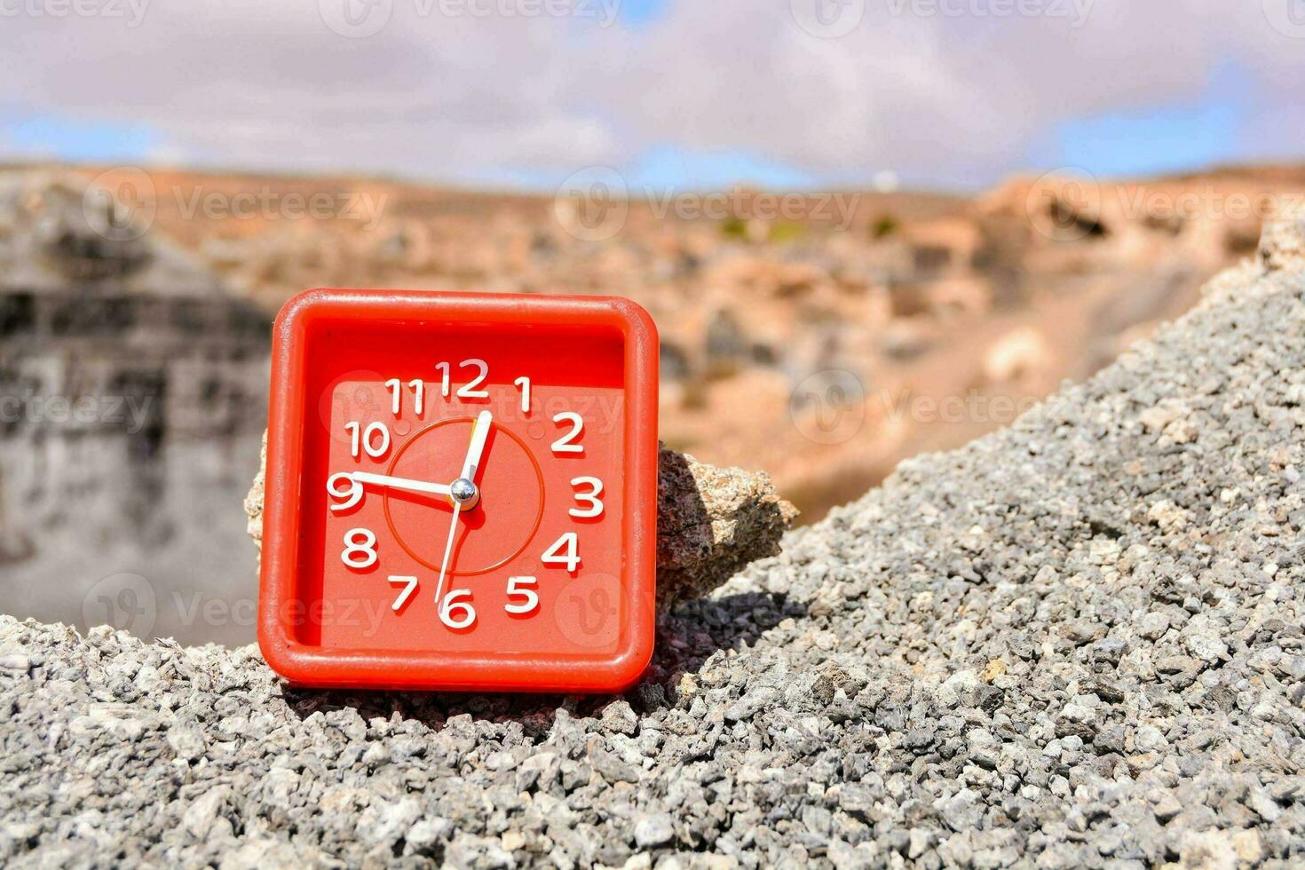 a red clock sitting on top of a pile of rocks photo