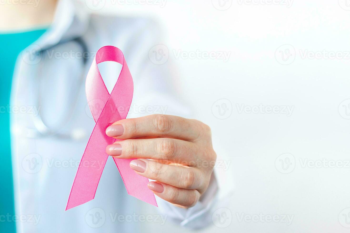 Breast Cancer Awareness Month. Female doctor in medical white uniform holds pink ribbon in her hands. Women's health care photo