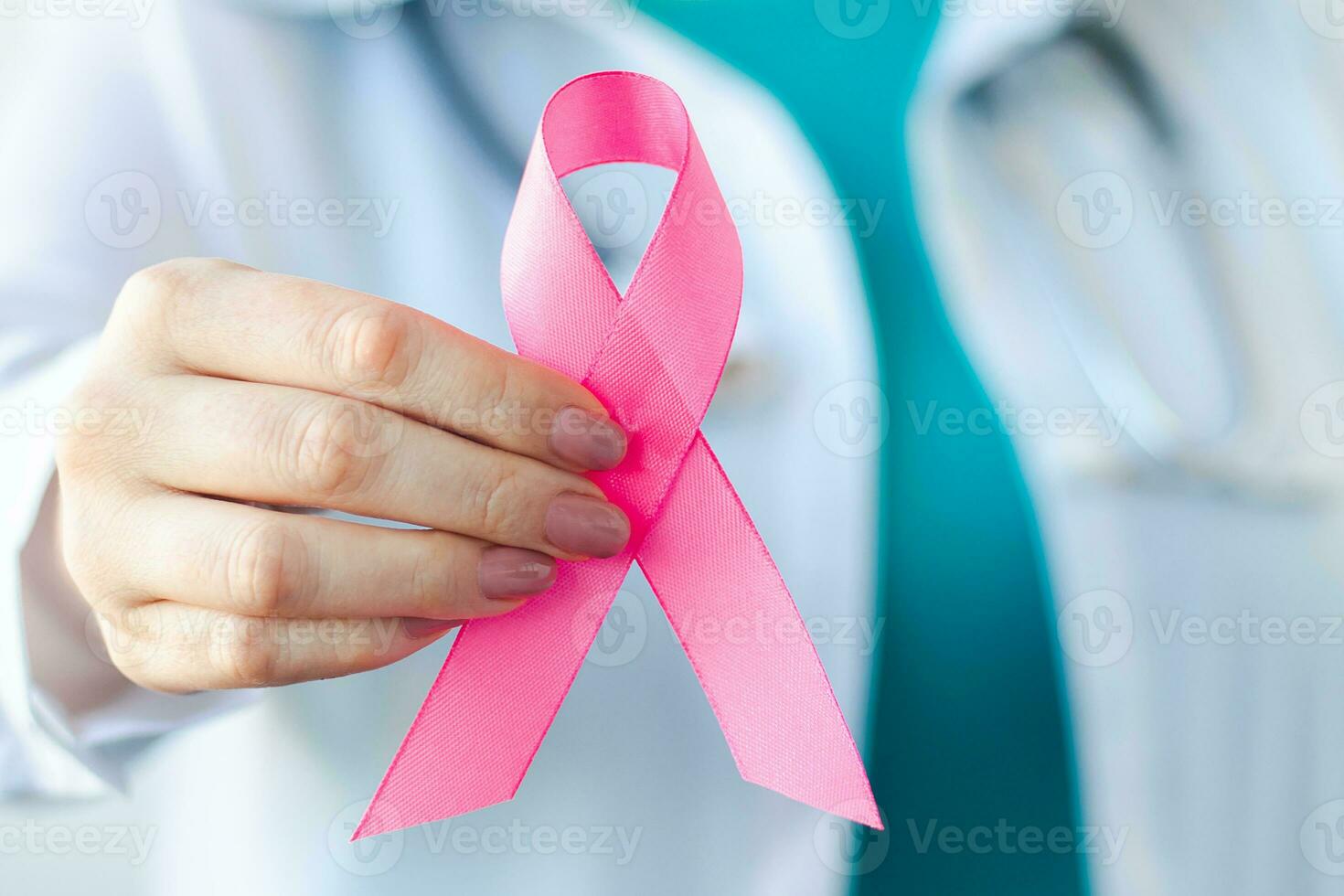 Breast Cancer Awareness Month. Female doctor in medical white uniform holds pink ribbon in her hands. Women's health care photo