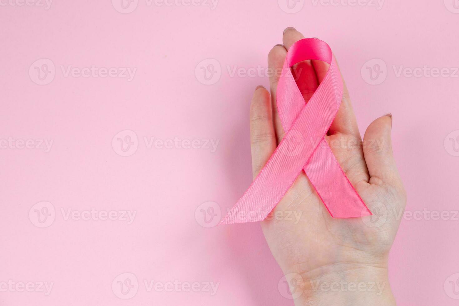 Breast Cancer Awareness Month. Woman's hand holds pink ribbon. Health care concept, cancer control symbol. photo