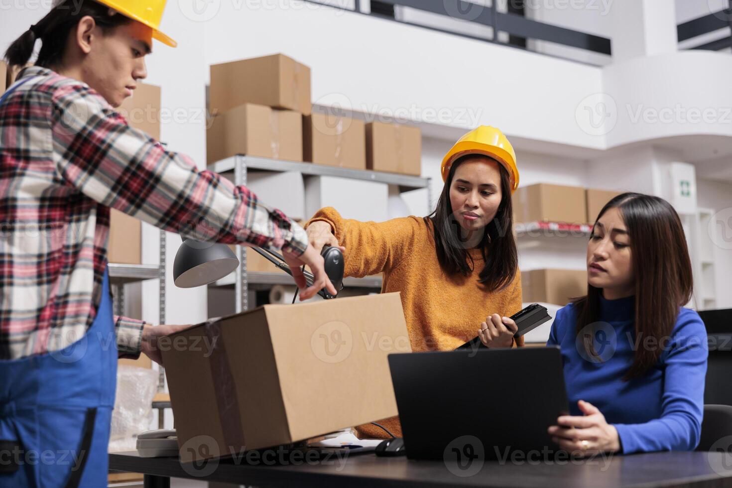 Asian package handler and delivery operators preparing parcel for shipment. Post office warehouse employees coworkers using barcode scanner and checking customer order on laptop photo