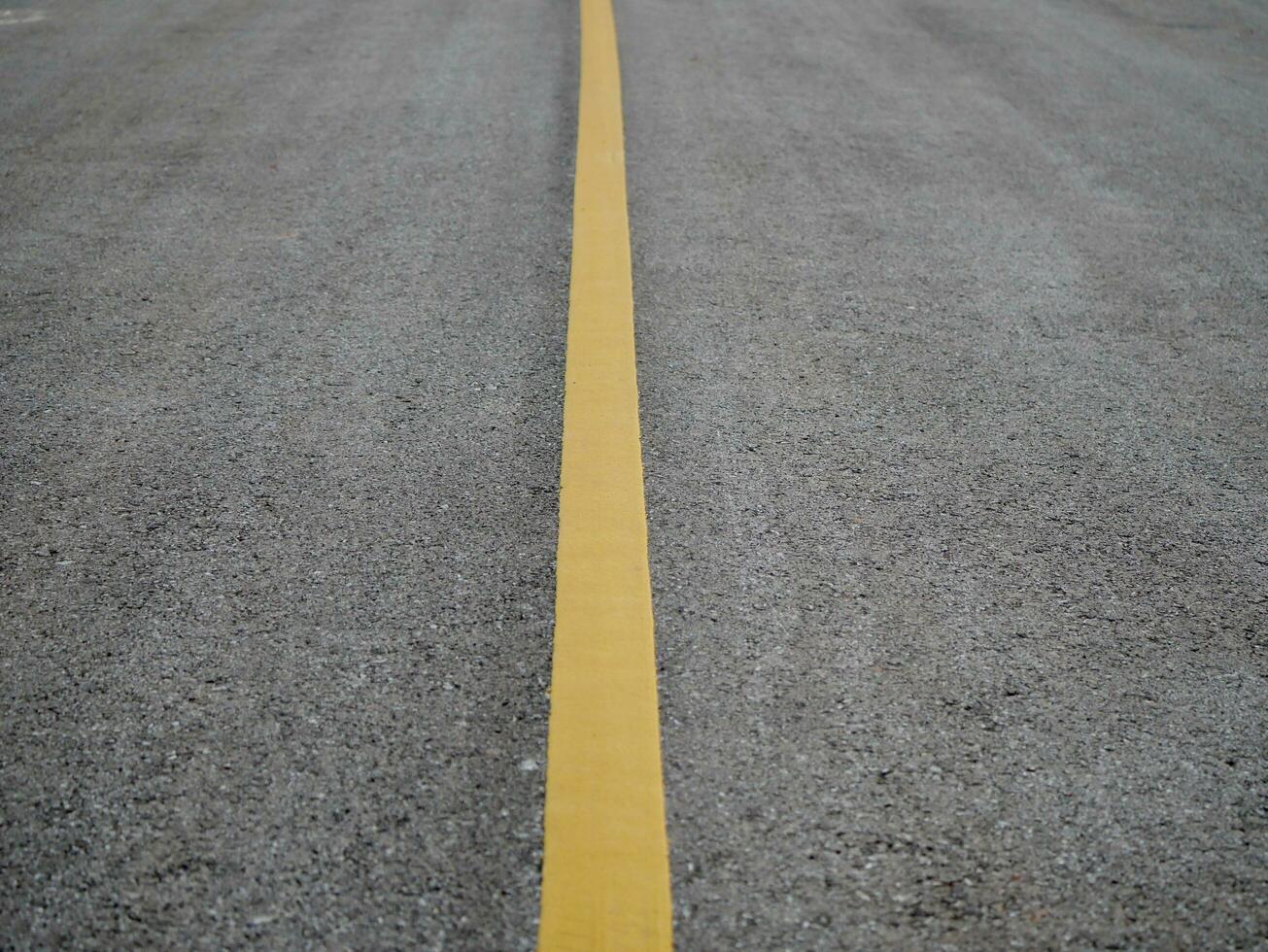 Asphalt road surface with yellow line, Surface grunge rough of asphalt, Dark grey with yellow line on the road and small rock, Texture Background, Top view photo