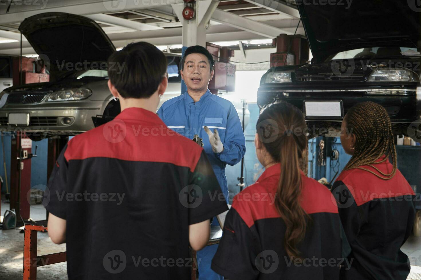 especialista conferencia, un masculino supervisor ingeniero tren y describir automotor motores con mecánico trabajador personal equipos para reparar trabajo a coche Servicio garaje y mantenimiento trabajos en automóvil industria. foto