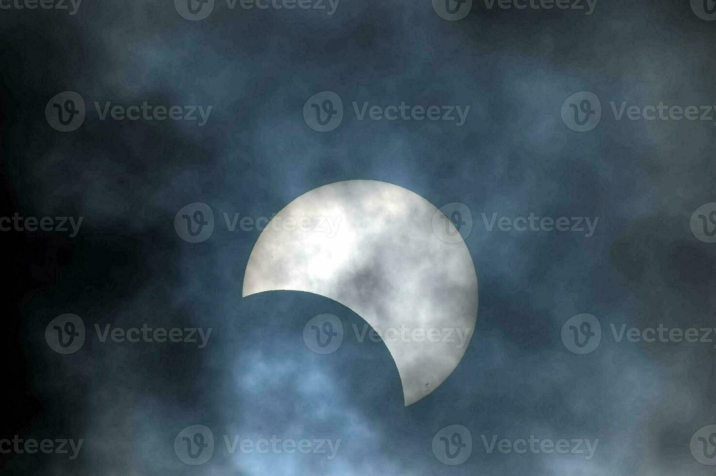 the moon is seen in the sky during a partial solar eclipse photo