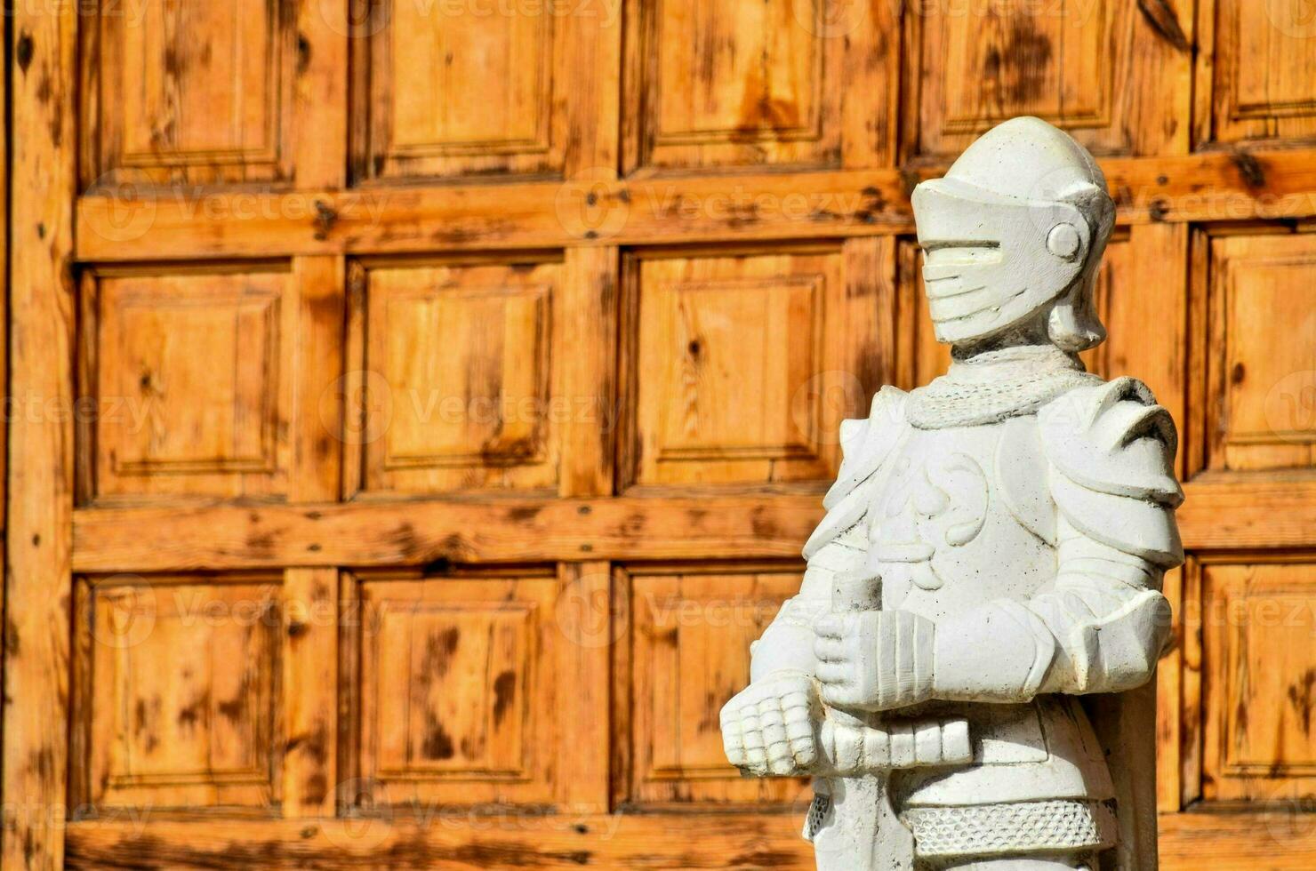 a statue of a knight standing in front of a wooden door photo