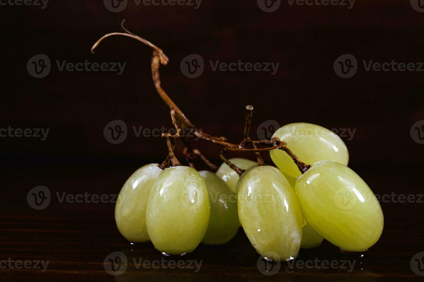 Small bunch of ripe green grapes on a wooden background. photo