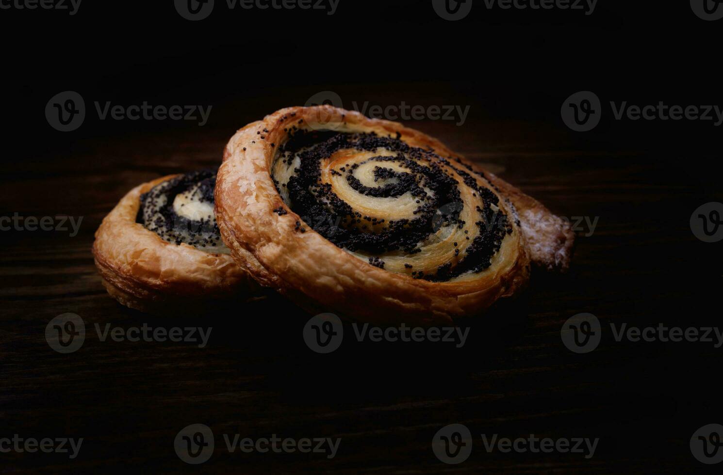 Two delicious buns with poppy seeds on a dark background. photo