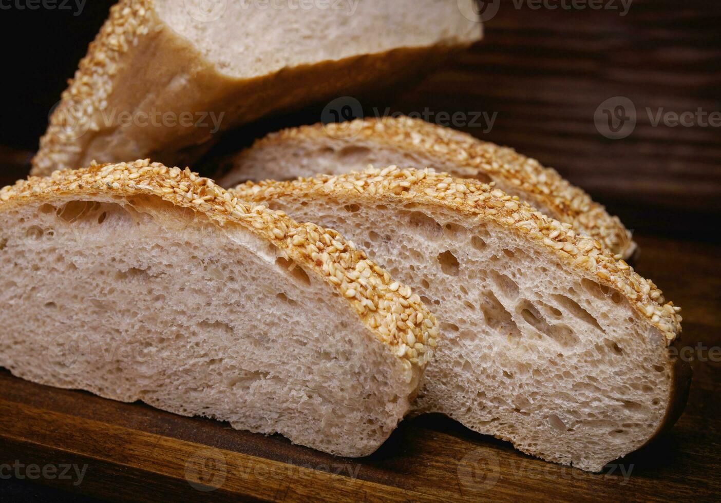 Cut loaf of bread and pieces of bread on a wooden background. Ciabatta bread. photo