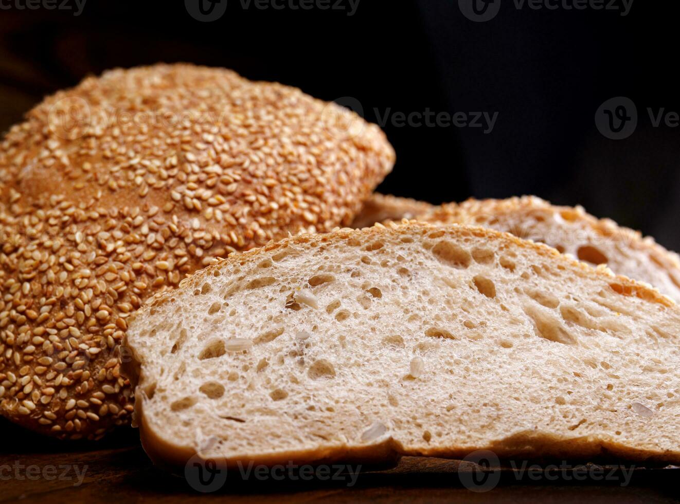 Cut loaf of bread and pieces of bread on a wooden background. Ciabatta bread. photo