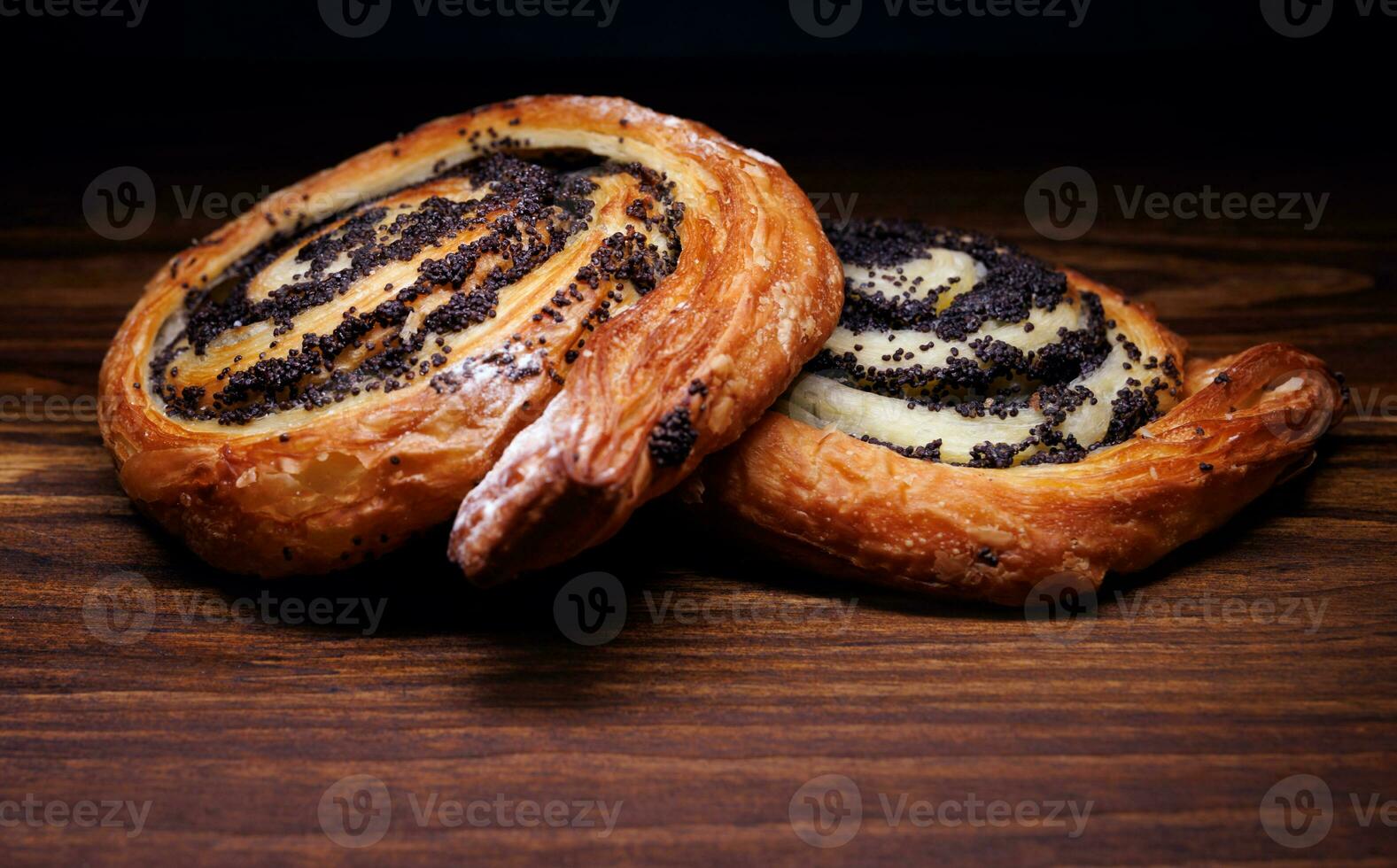 Two delicious buns with poppy seeds lie on a wooden background. photo