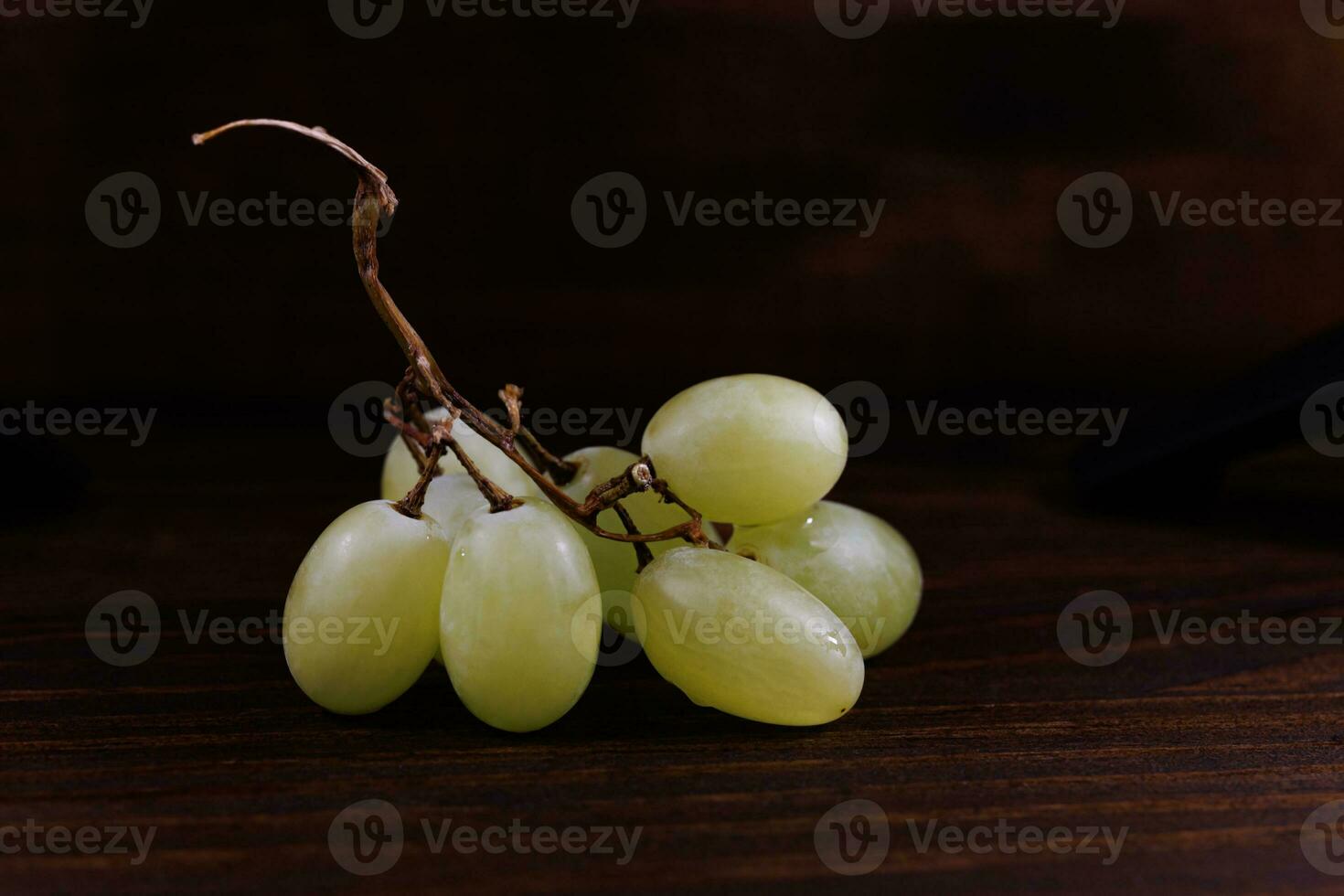 Small bunch of ripe green grapes on a wooden background. photo