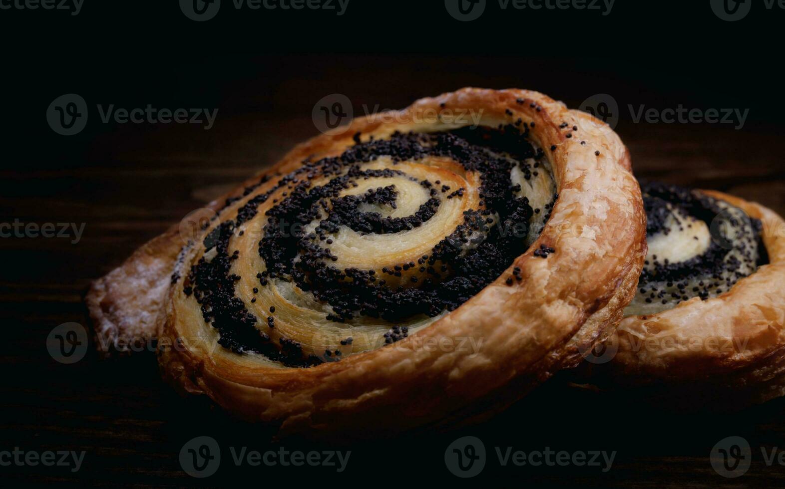 Two delicious buns with poppy seeds on a dark background. photo