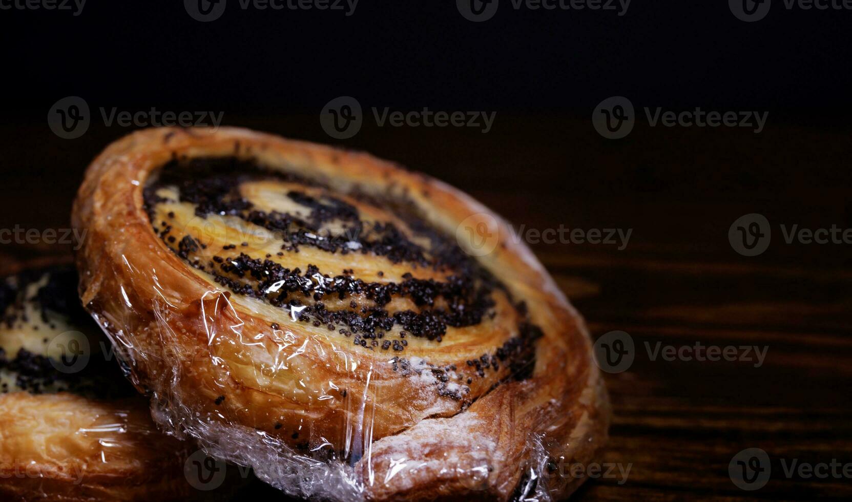 Two poppy seed buns wrapped in plastic wrap. photo