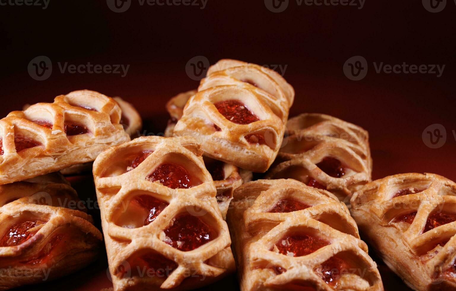 Puff pastry pastry with lingonberry jam on a dark red background. Cookies with lingonberry jam. photo