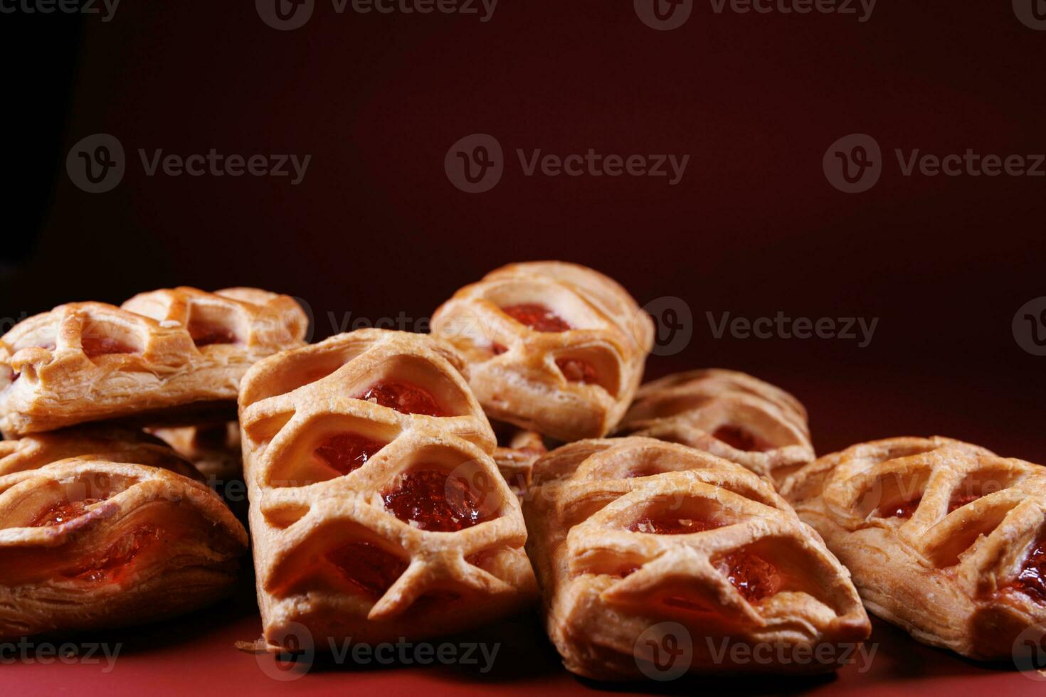 Puff pastry pastry with lingonberry jam on a dark red background. Cookies with lingonberry jam. photo