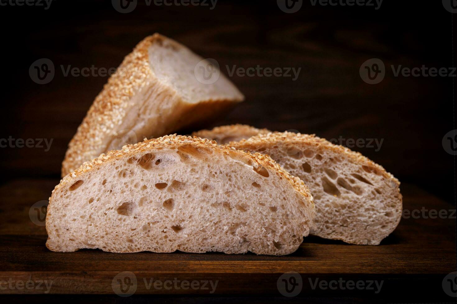 Cut loaf of bread and pieces of bread on a wooden background. Ciabatta bread. photo