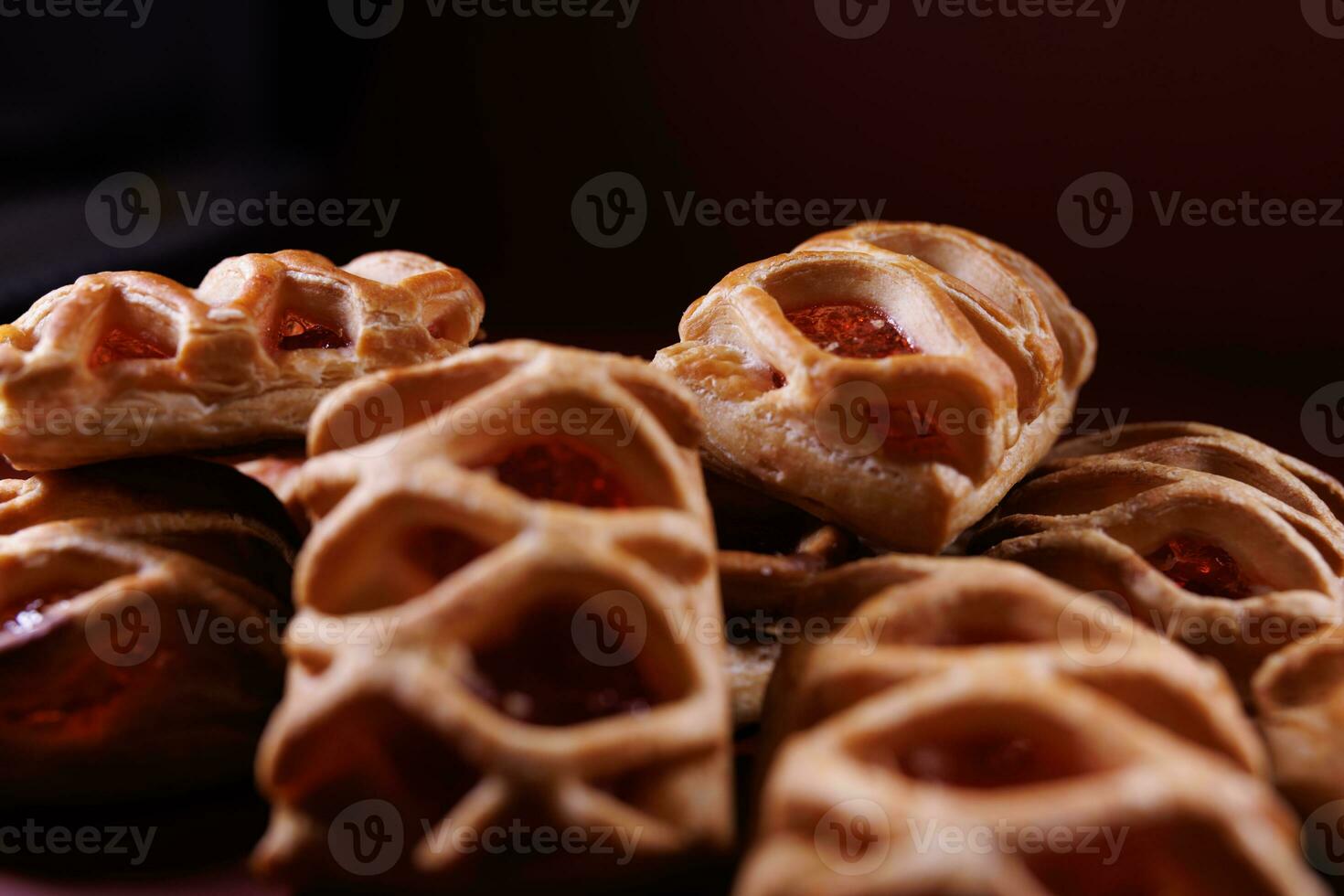 Puff pastry pastry with lingonberry jam on a dark red background. Cookies with lingonberry jam. photo