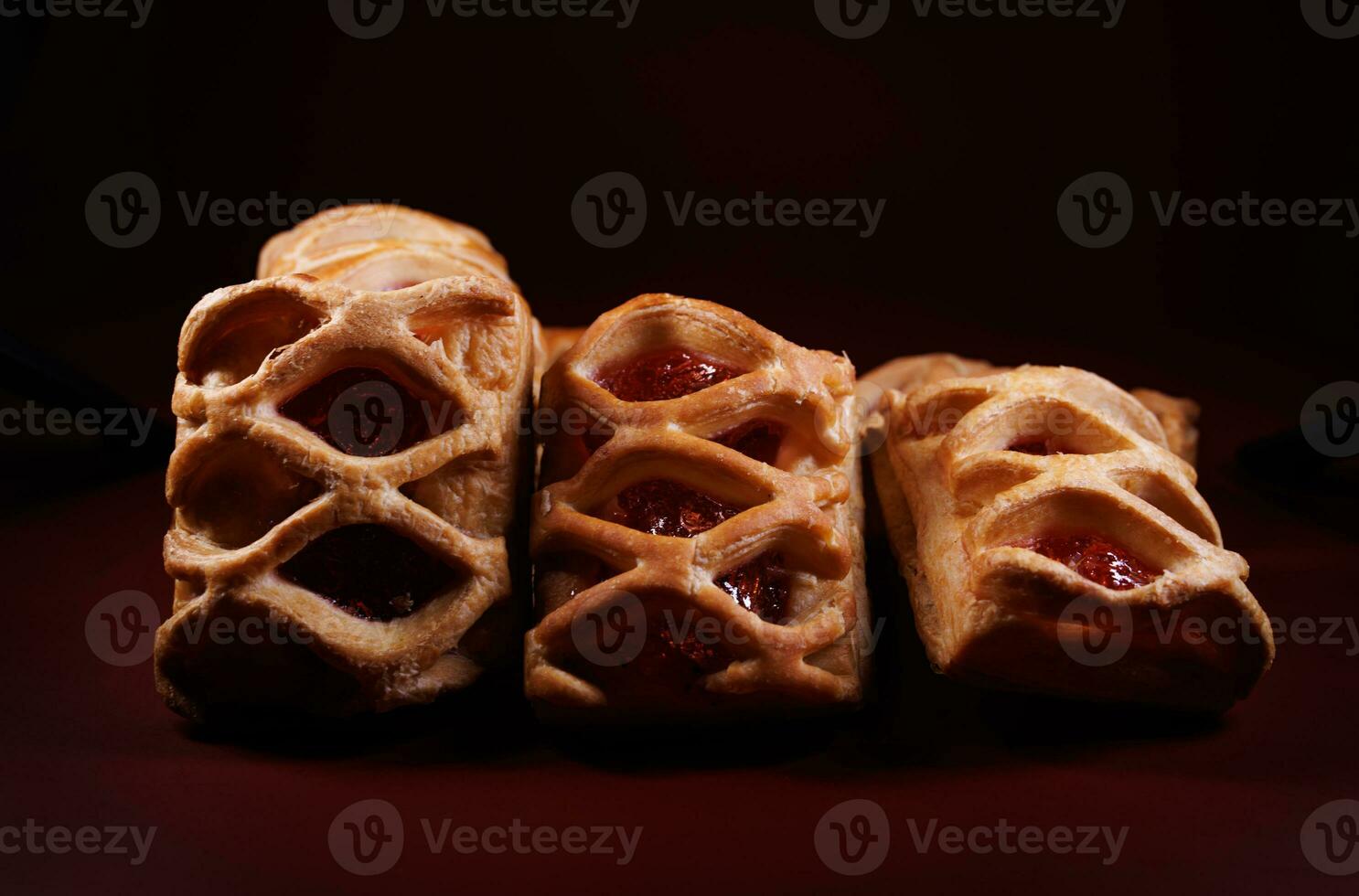 Puff pastry pastry with lingonberry jam on a dark red background. Cookies with lingonberry jam. photo