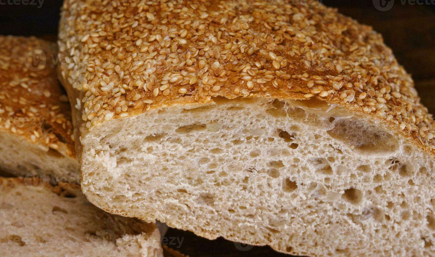 Cut loaf of bread and pieces of bread on a wooden background. Ciabatta bread. photo