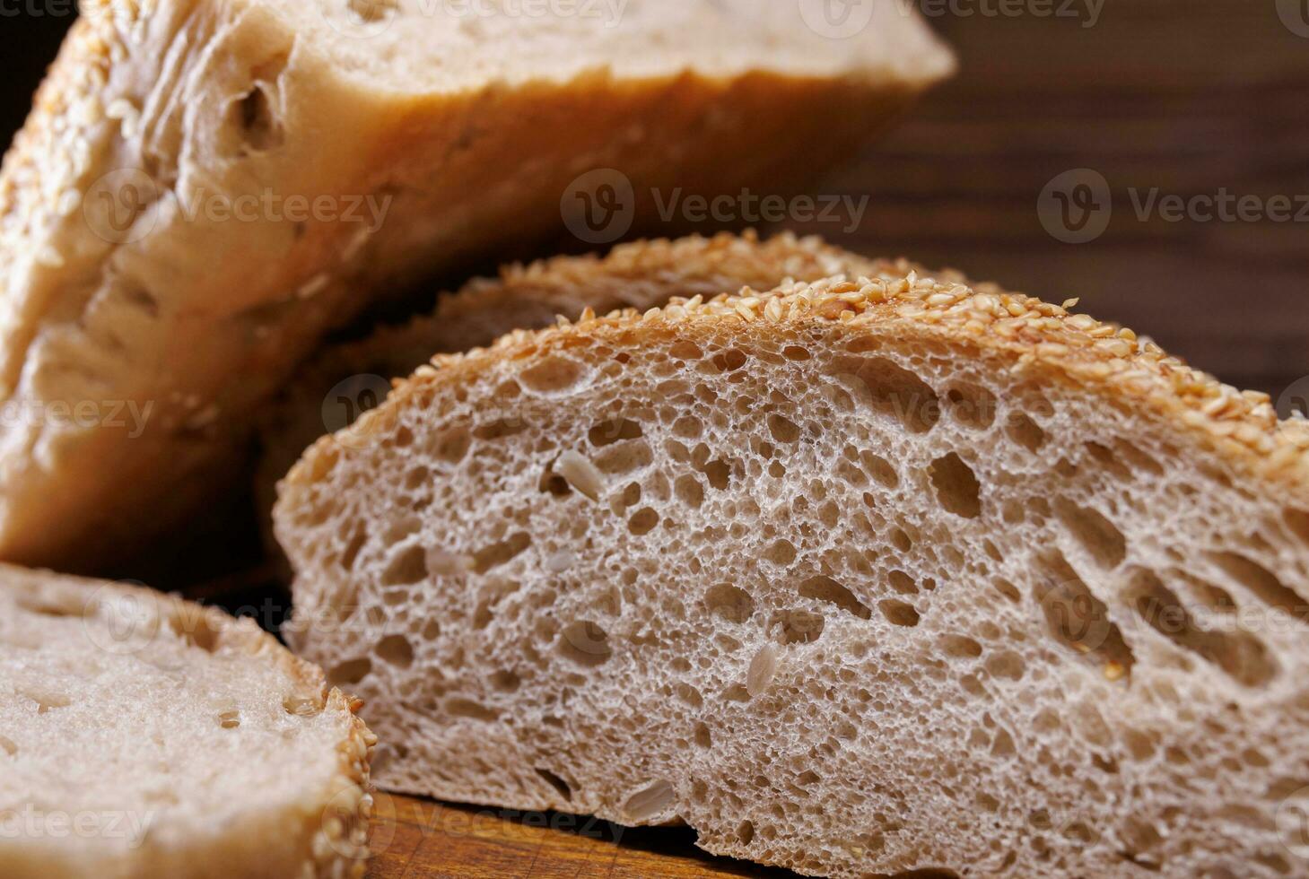 Cut loaf of bread and pieces of bread on a wooden background. Ciabatta bread. photo