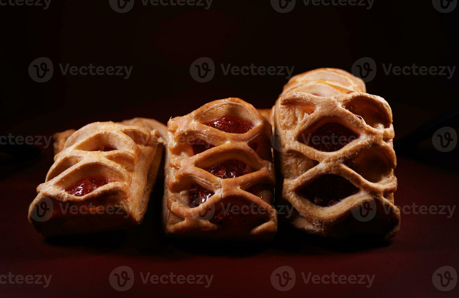 Puff pastry pastry with lingonberry jam on a dark red background. Cookies with lingonberry jam. photo