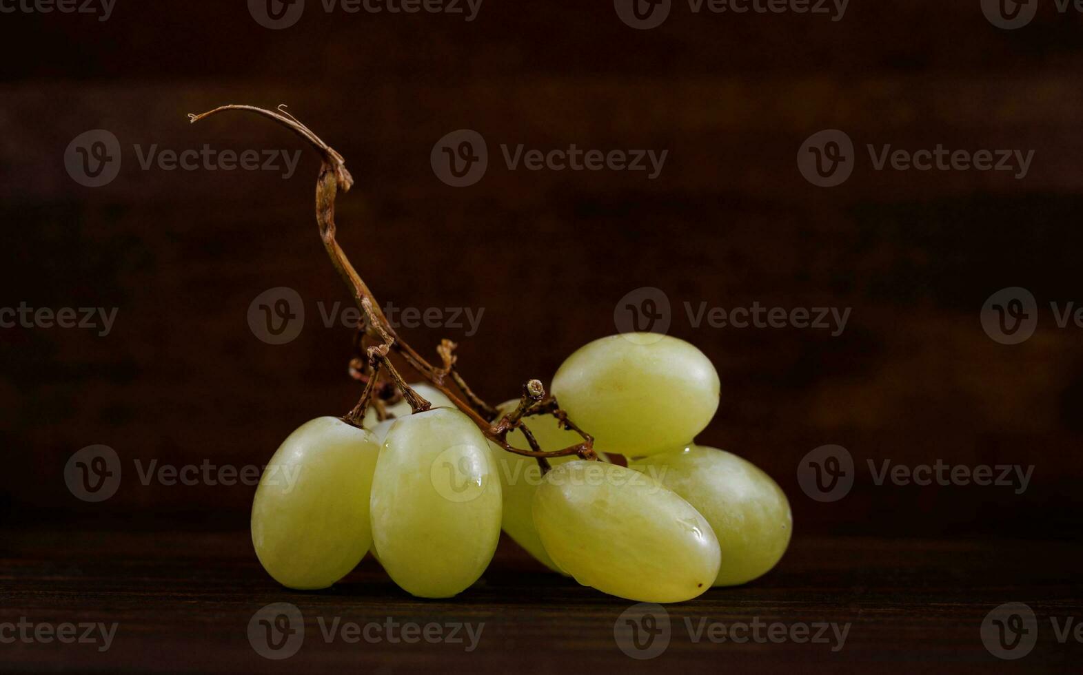 Small bunch of ripe green grapes on a wooden background. photo