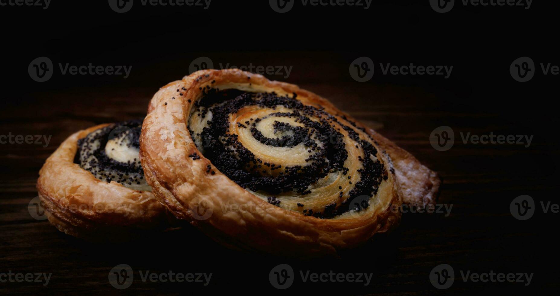 Two delicious buns with poppy seeds on a dark background. photo