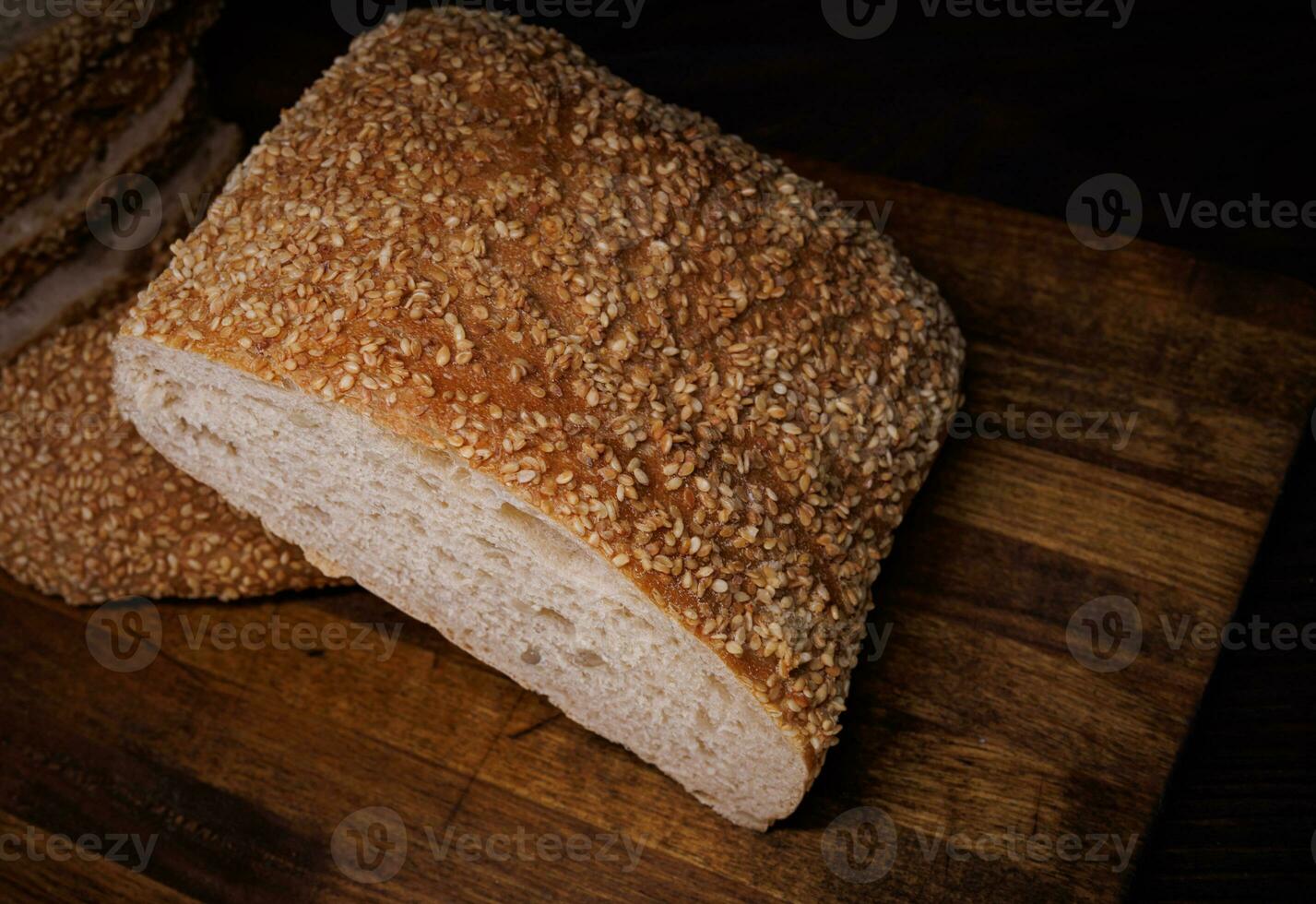 Cut loaf of bread and pieces of bread on a wooden background. Ciabatta bread. photo