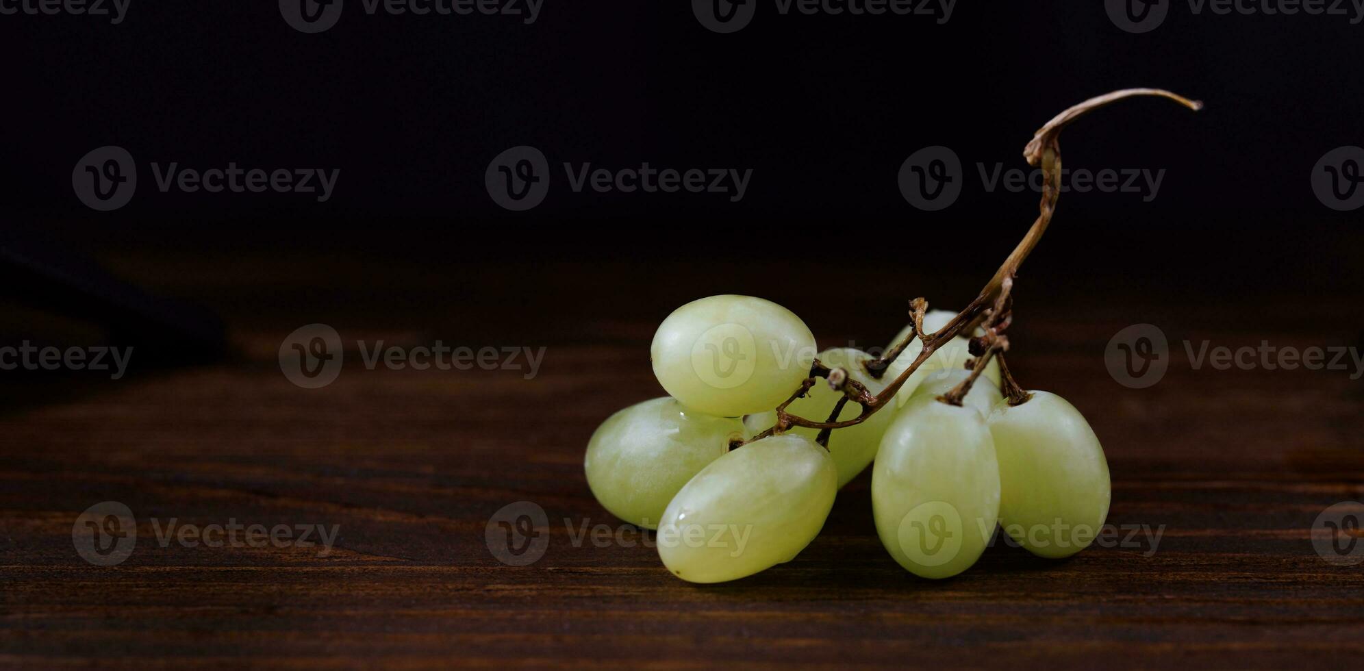 Small bunch of ripe green grapes on a wooden background. photo