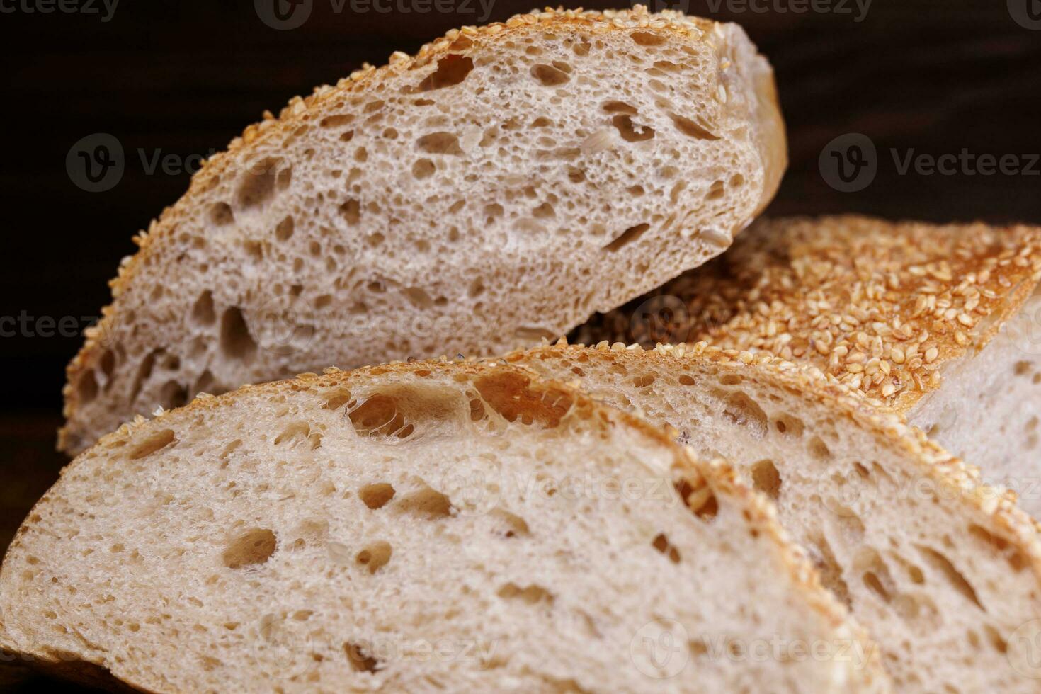 Cut loaf of bread and pieces of bread on a wooden background. Ciabatta bread. photo