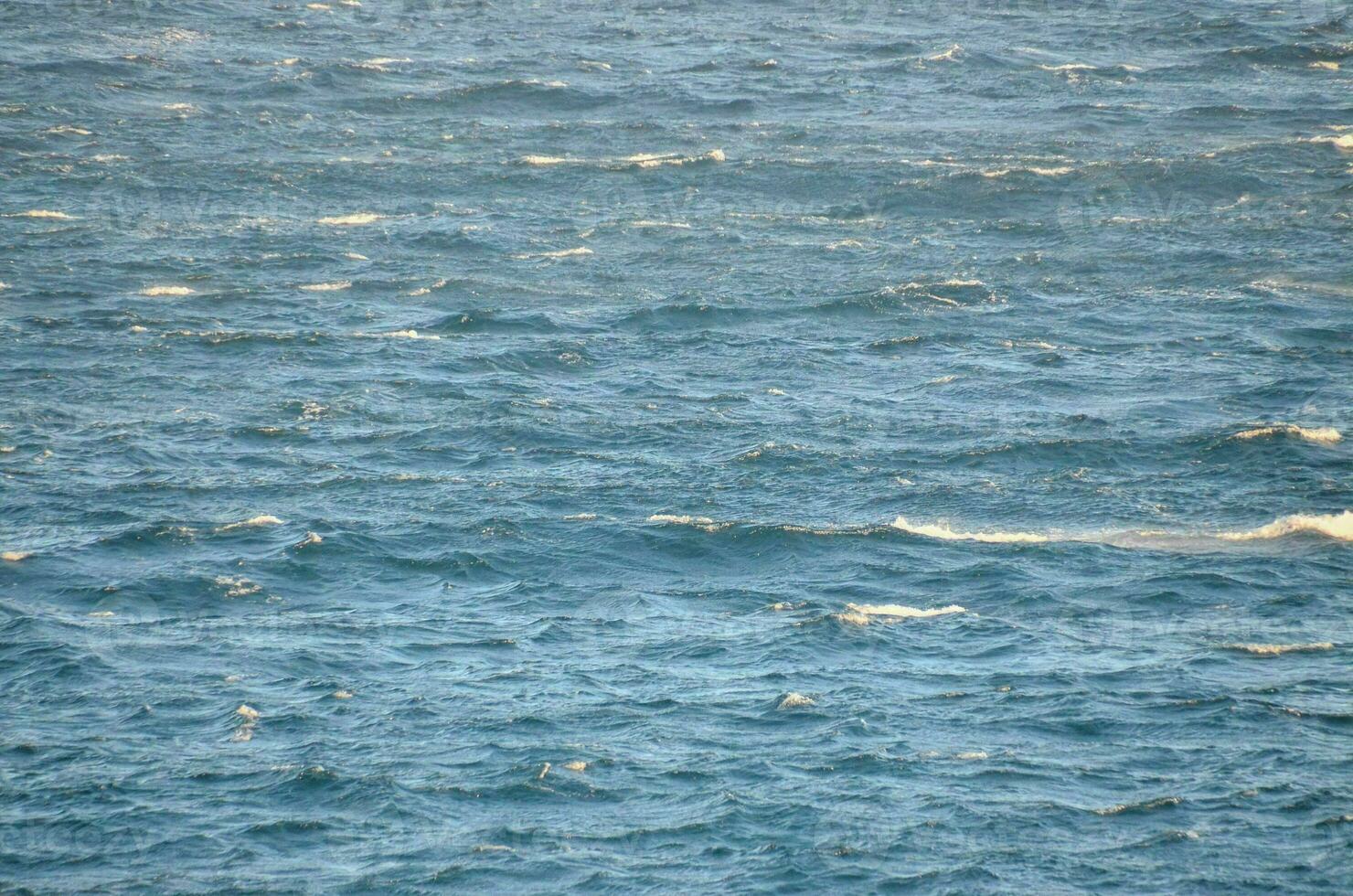 a large body of water with waves and a boat in the middle photo