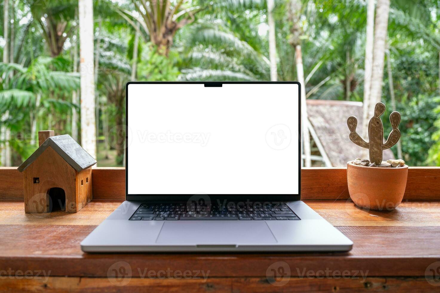 Blank screen of Laptop computer on wooden table with garden view photo