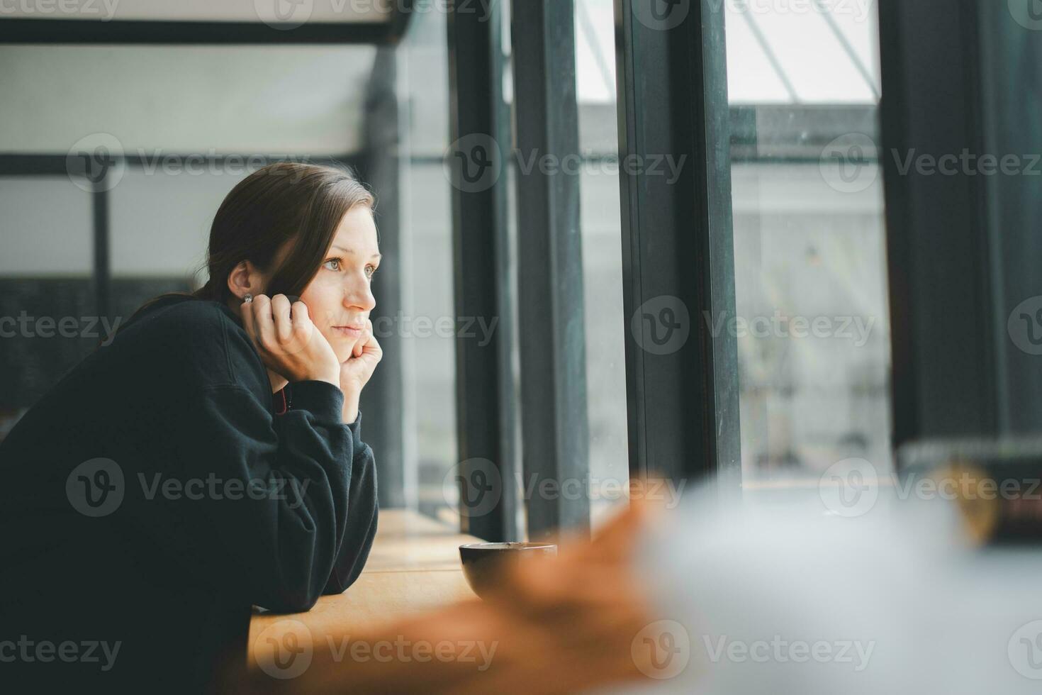 Sad woman sitting by the window looking outside photo