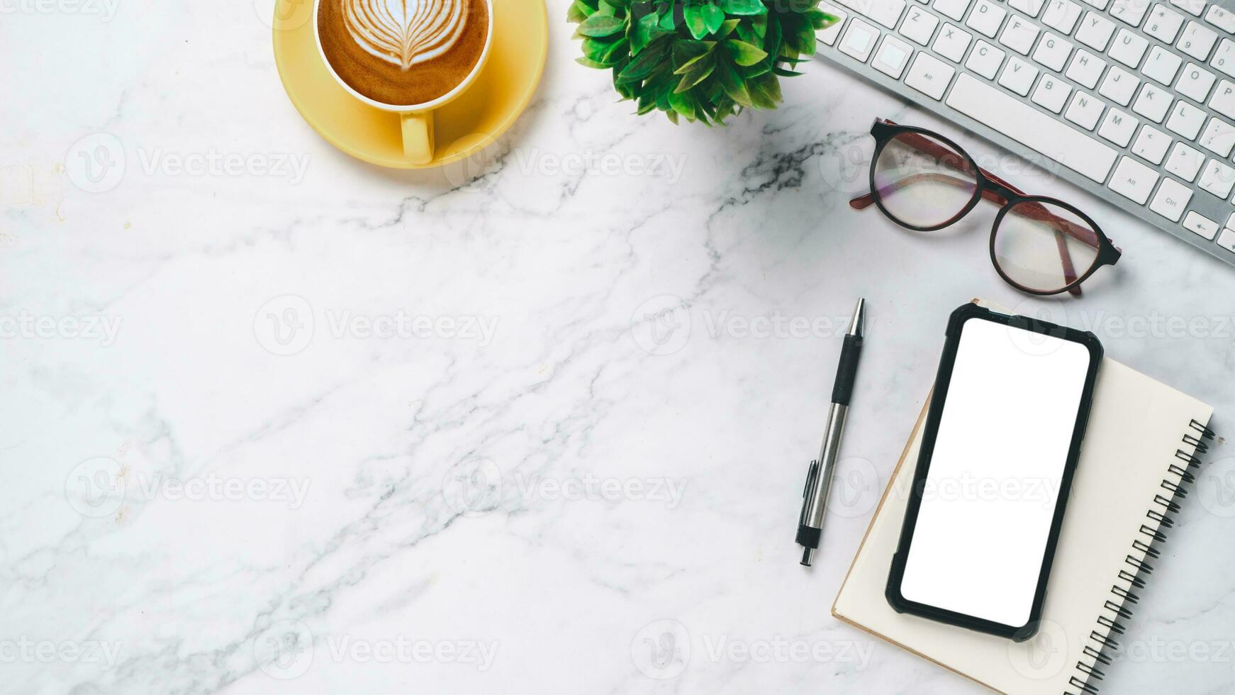 blanco oficina escritorio con teclado computadora, lente, bolígrafo, blanco pantalla inteligente teléfono, cuaderno y taza de café, parte superior ver con Copiar espacio, burlarse de arriba. foto