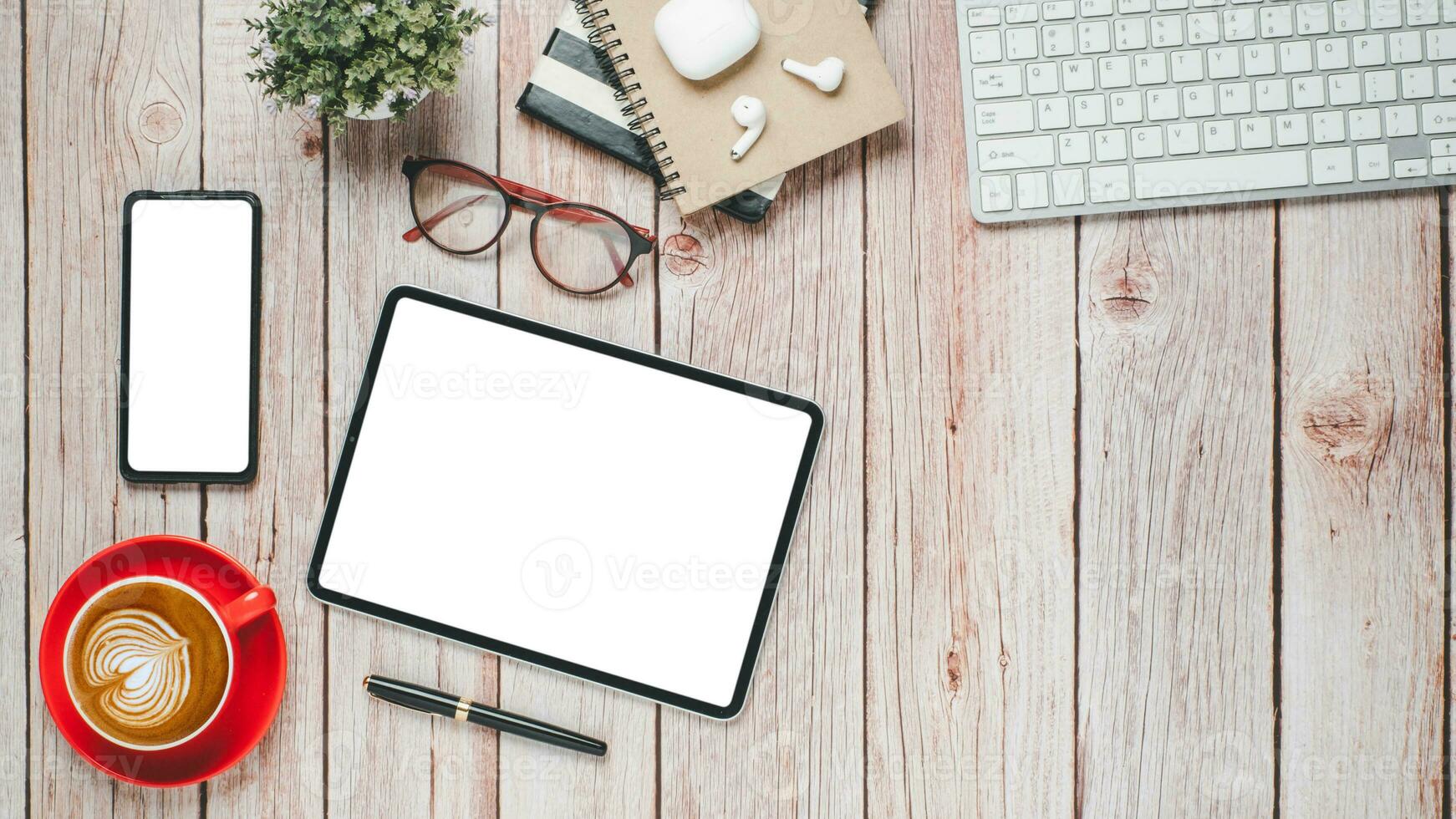 Wooden desk workplace with blank screen tablet and smartphone, keyboard, pen, eyeglass, notebook and cup of coffee, Top view flat lay with copy space. photo