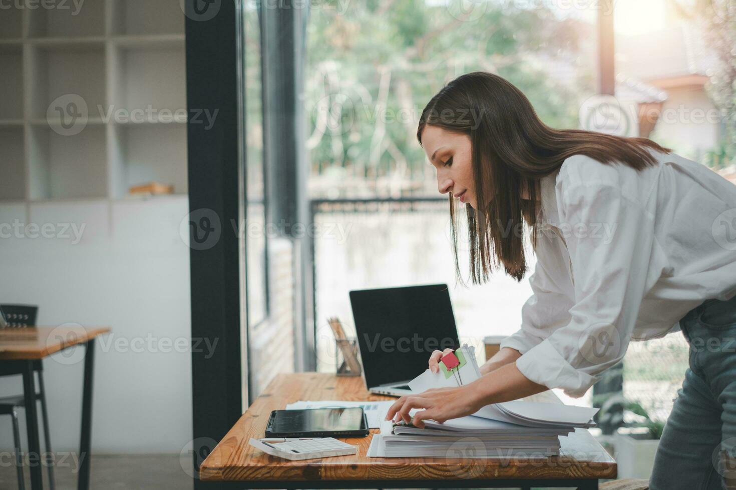 Businesswoman working in Stacks of paper files for searching and checking unfinished document achieves on folders papers at busy work desk office photo