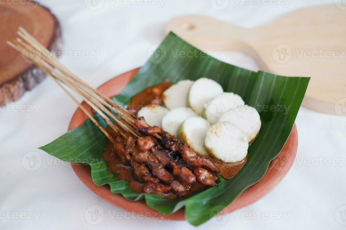 chicken satay on a white plate with peanut sauce photo