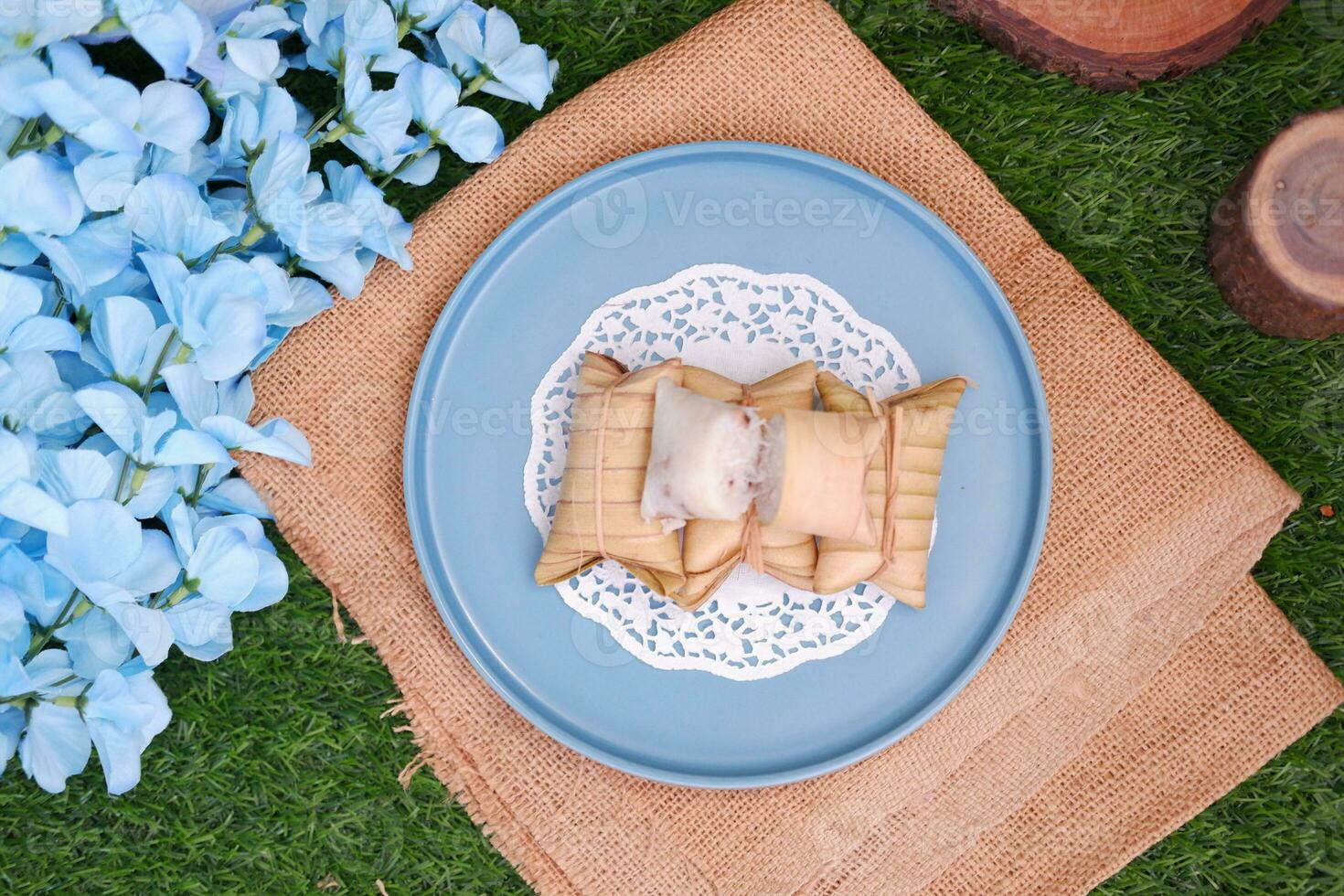 Lepet or Leupeut is a type of snack made from glutinous rice mixed with peanuts, cooked in coconut milk, then wrapped in coconut leaves. Close up view photo