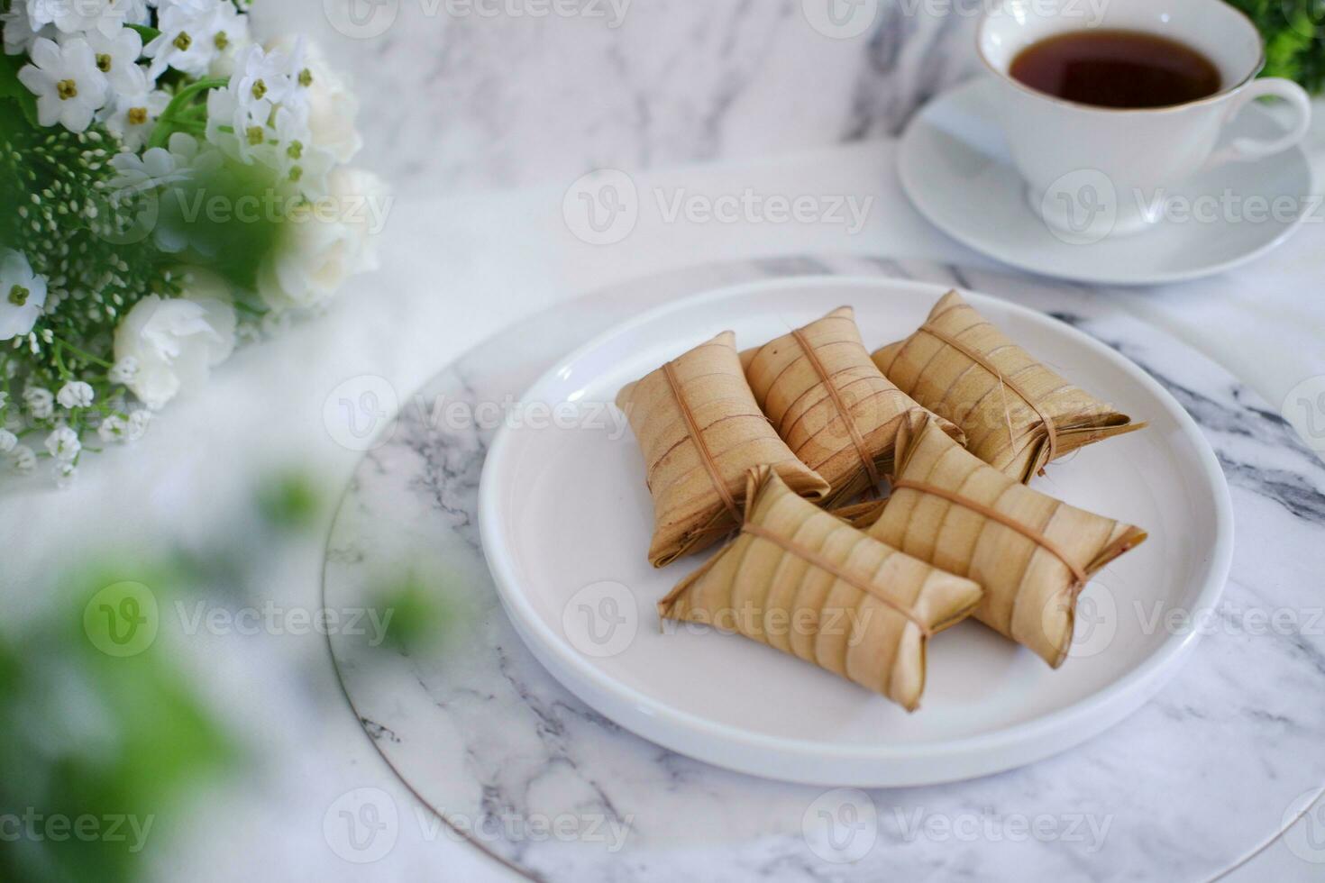 Lepet or Leupeut is a type of snack made from glutinous rice mixed with peanuts, cooked in coconut milk, then wrapped in coconut leaves. Close up view photo