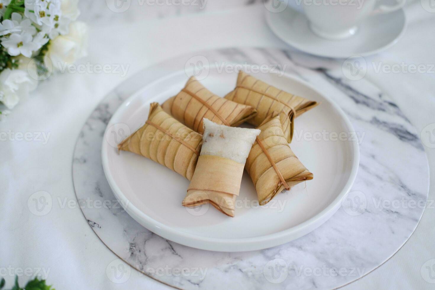 Lepet or Leupeut is a type of snack made from glutinous rice mixed with peanuts, cooked in coconut milk, then wrapped in coconut leaves. Close up view photo