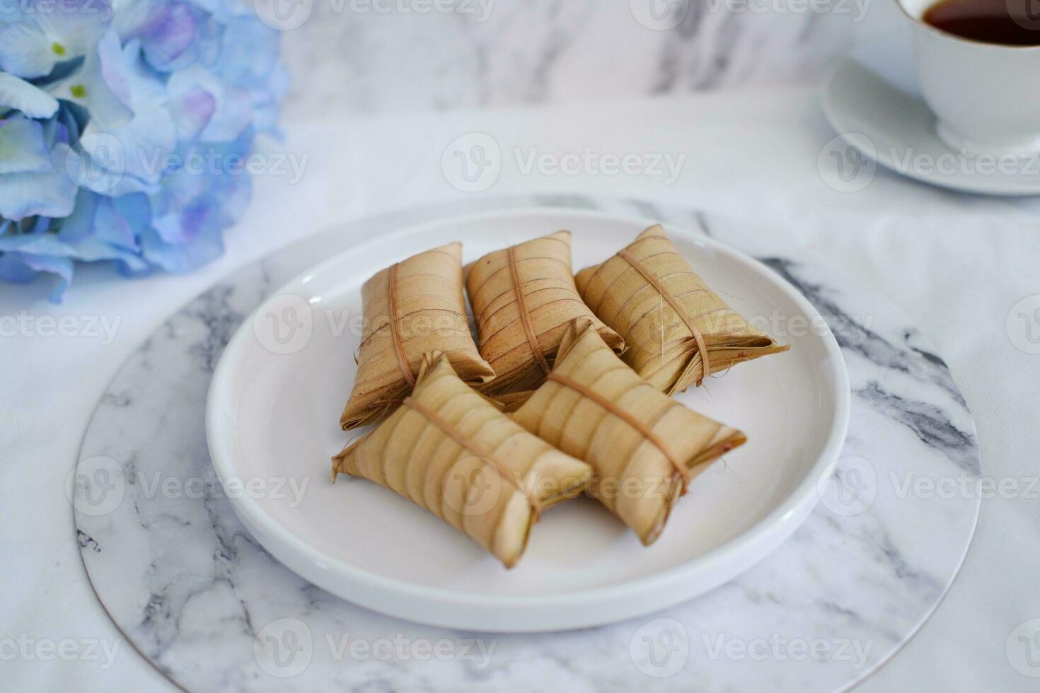 Lepet or Leupeut is a type of snack made from glutinous rice mixed with peanuts, cooked in coconut milk, then wrapped in coconut leaves. Close up view photo
