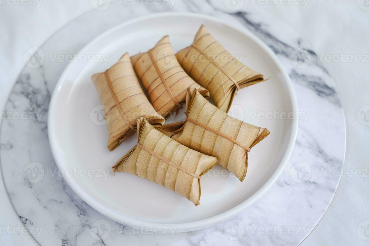 Lepet or Leupeut is a type of snack made from glutinous rice mixed with peanuts, cooked in coconut milk, then wrapped in coconut leaves. Close up view photo