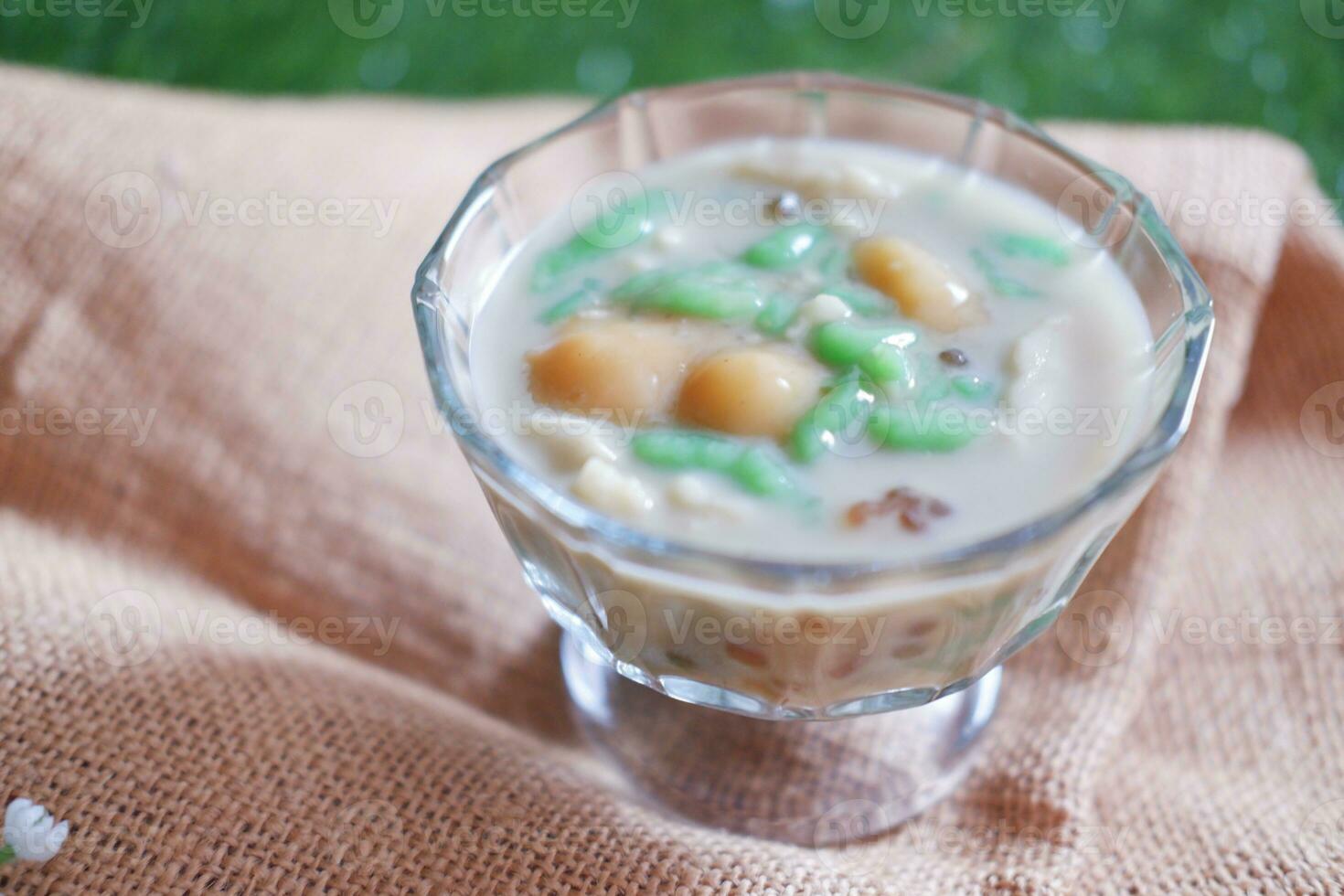 coconut milk in small glass on green grass background photo