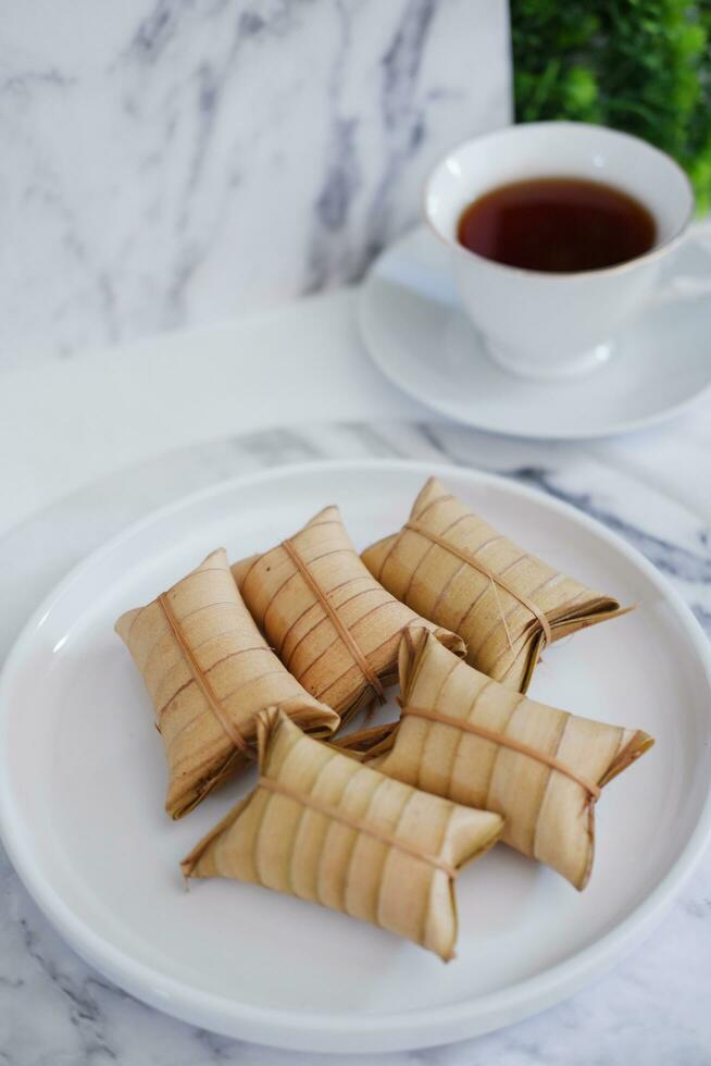Lepet or Leupeut is a type of snack made from glutinous rice mixed with peanuts, cooked in coconut milk, then wrapped in coconut leaves. Close up view photo
