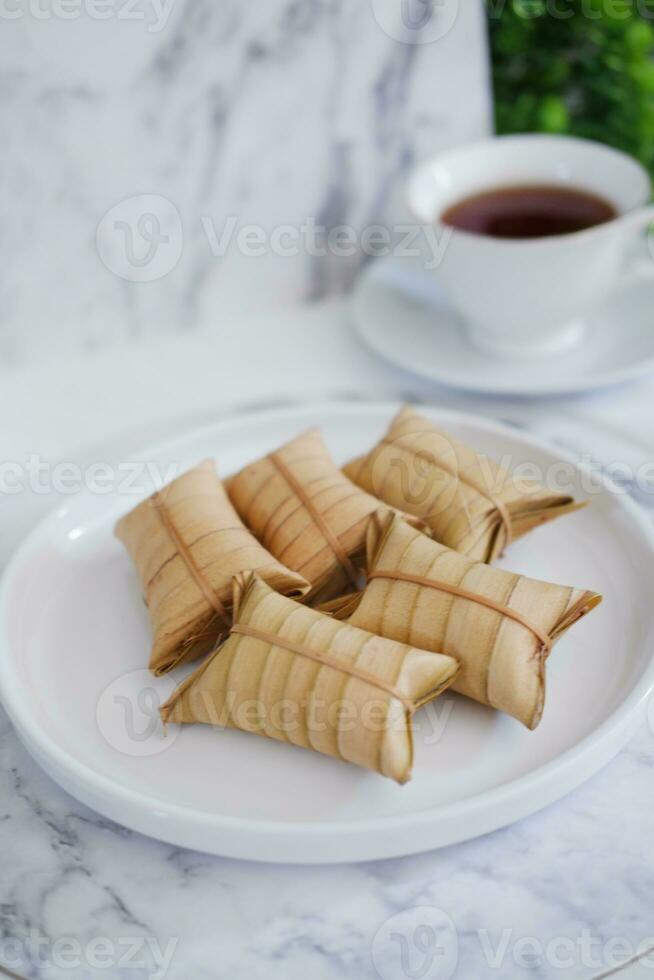 Lepet or Leupeut is a type of snack made from glutinous rice mixed with peanuts, cooked in coconut milk, then wrapped in coconut leaves. Close up view photo