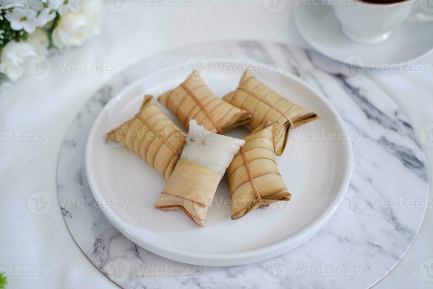 Lepet or Leupeut is a type of snack made from glutinous rice mixed with peanuts, cooked in coconut milk, then wrapped in coconut leaves. Close up view photo