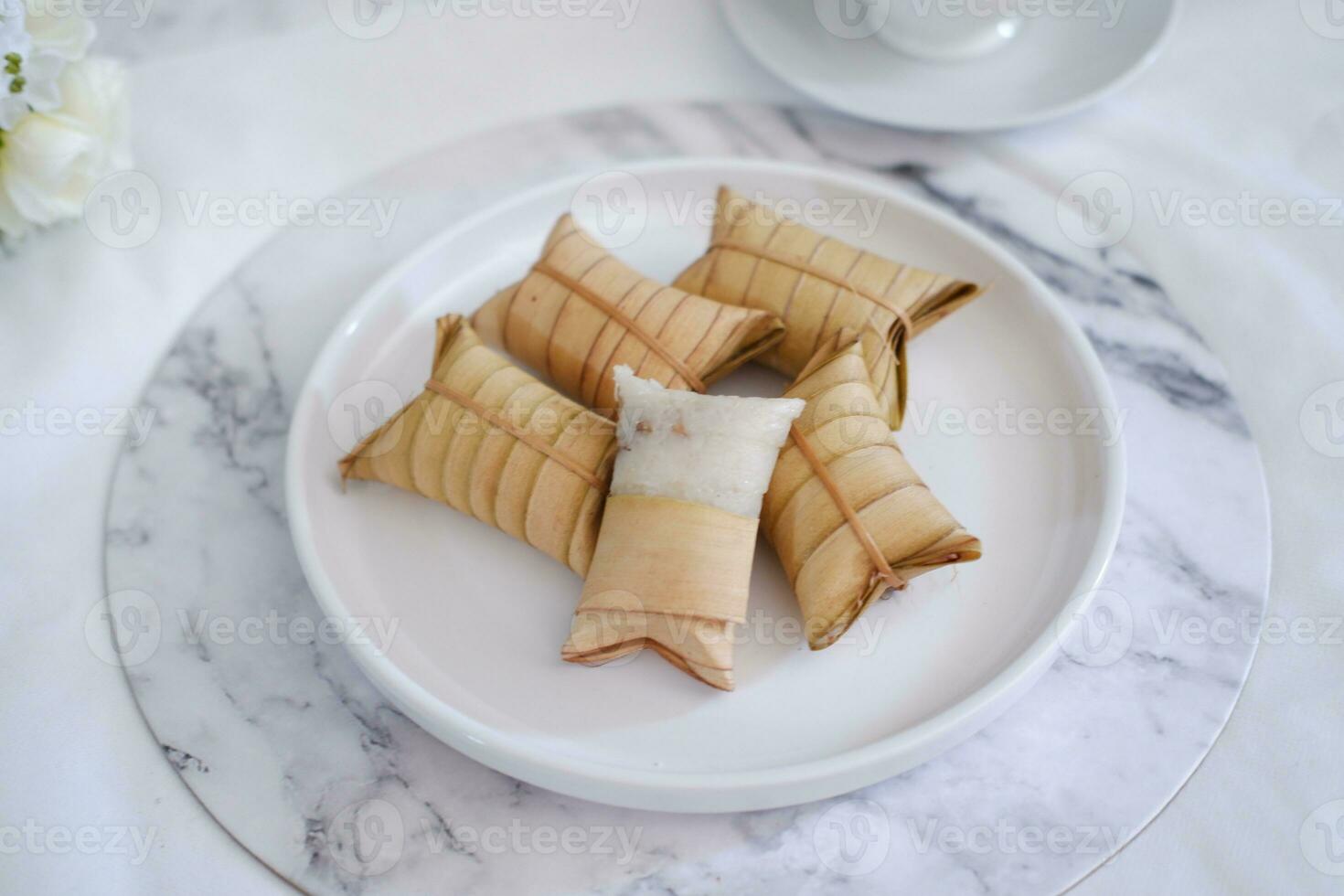 Lepet or Leupeut is a type of snack made from glutinous rice mixed with peanuts, cooked in coconut milk, then wrapped in coconut leaves. Close up view photo