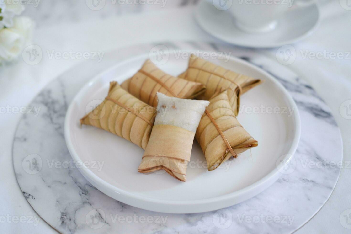 Lepet or Leupeut is a type of snack made from glutinous rice mixed with peanuts, cooked in coconut milk, then wrapped in coconut leaves. Close up view photo