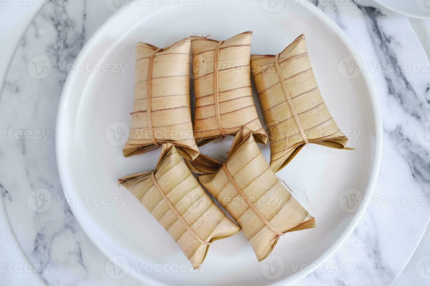 Lepet or Leupeut is a type of snack made from glutinous rice mixed with peanuts, cooked in coconut milk, then wrapped in coconut leaves. Close up view photo